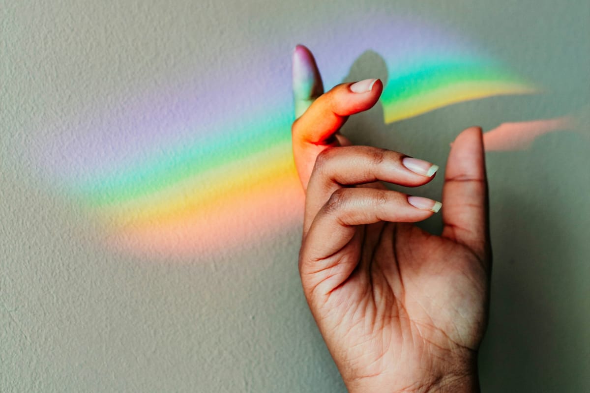 Glass prism with light shining through it, creating a spectrum of rainbow colours.